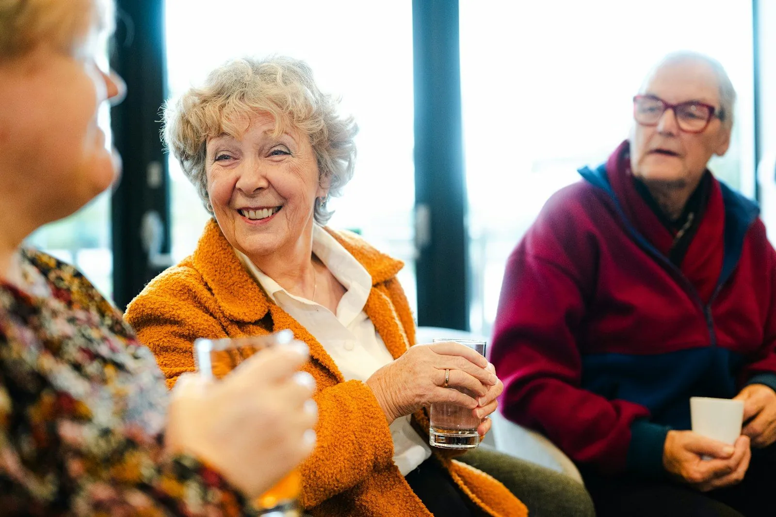 Three older friends laughing together over coffee